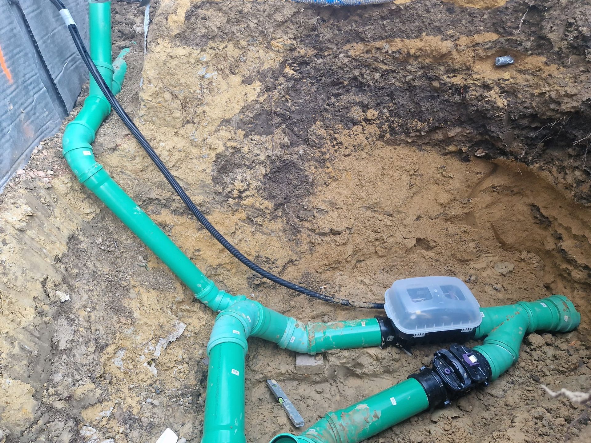 Ein Haufen grüner Rohre liegen im Dreck