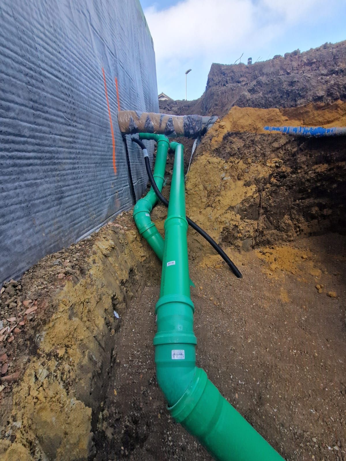 In einem Loch im Boden wird ein grünes Rohr installiert.