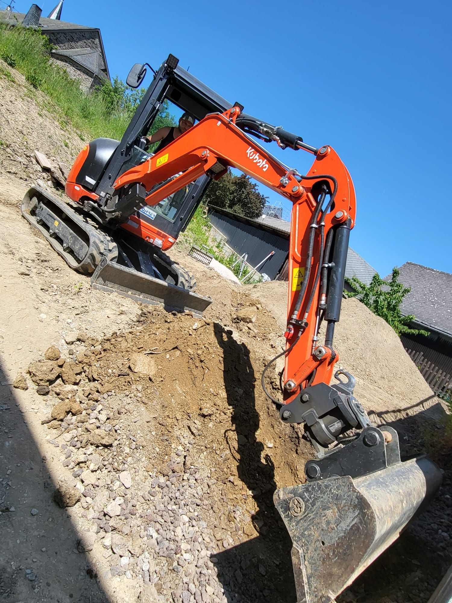 Ein orange-schwarzer Bagger gräbt ein Loch in den Boden.