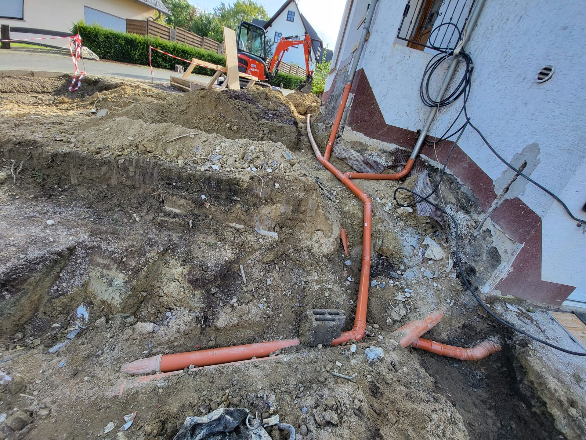 Vor einem Haus liegen mehrere Rohre im Dreck.