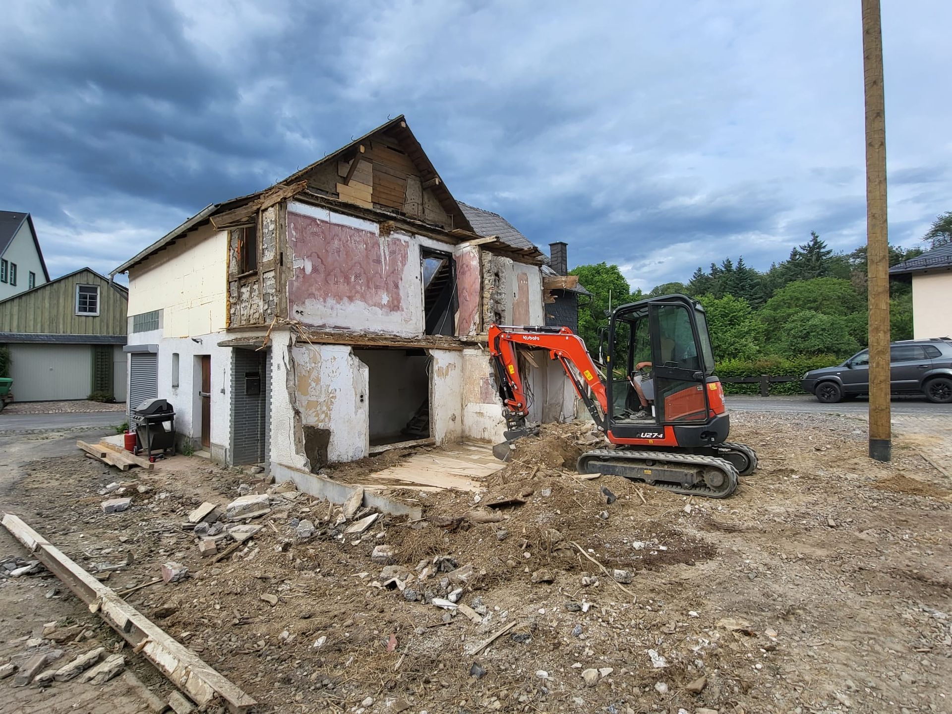 Ein Haus wird mit einem kleinen Bagger abgerissen.