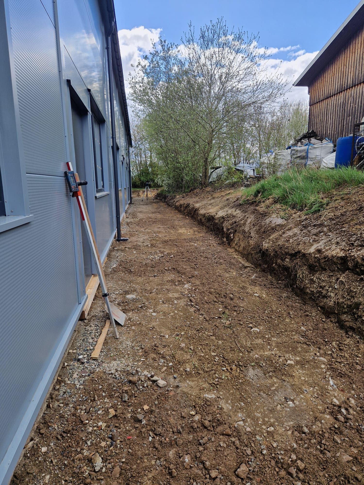 Ein Feldweg, der zu einem Gebäude mit Schaufel und Rechen führt.