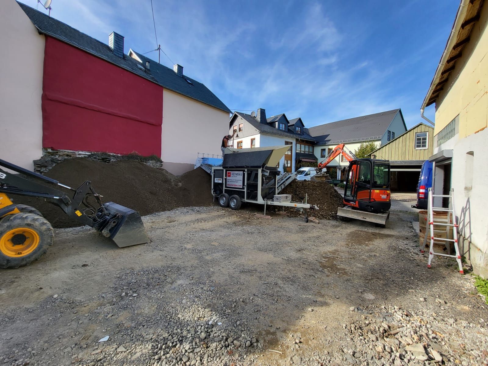 Vor einem Gebäude liegt ein großer Erdhaufen.