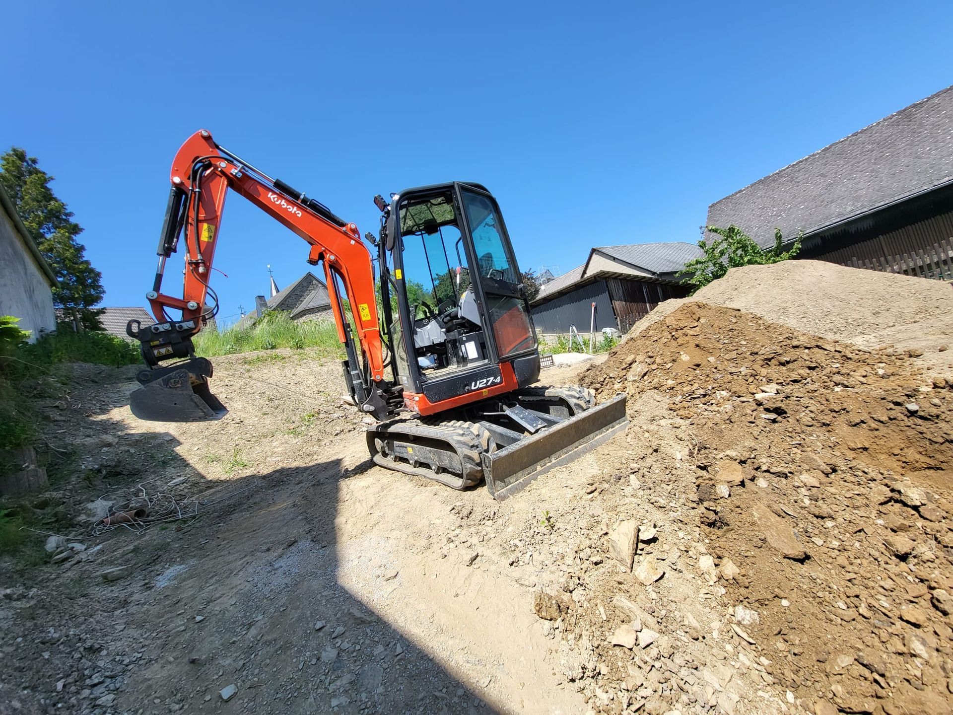 Ein kleiner Bagger steht auf einem Erdhaufen.