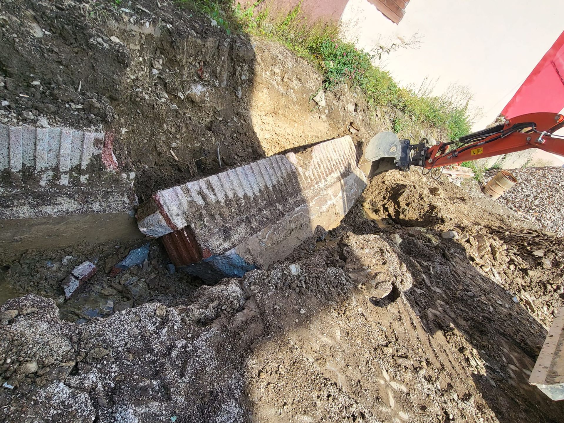 Ein roter Bagger gräbt ein Loch in den Boden.