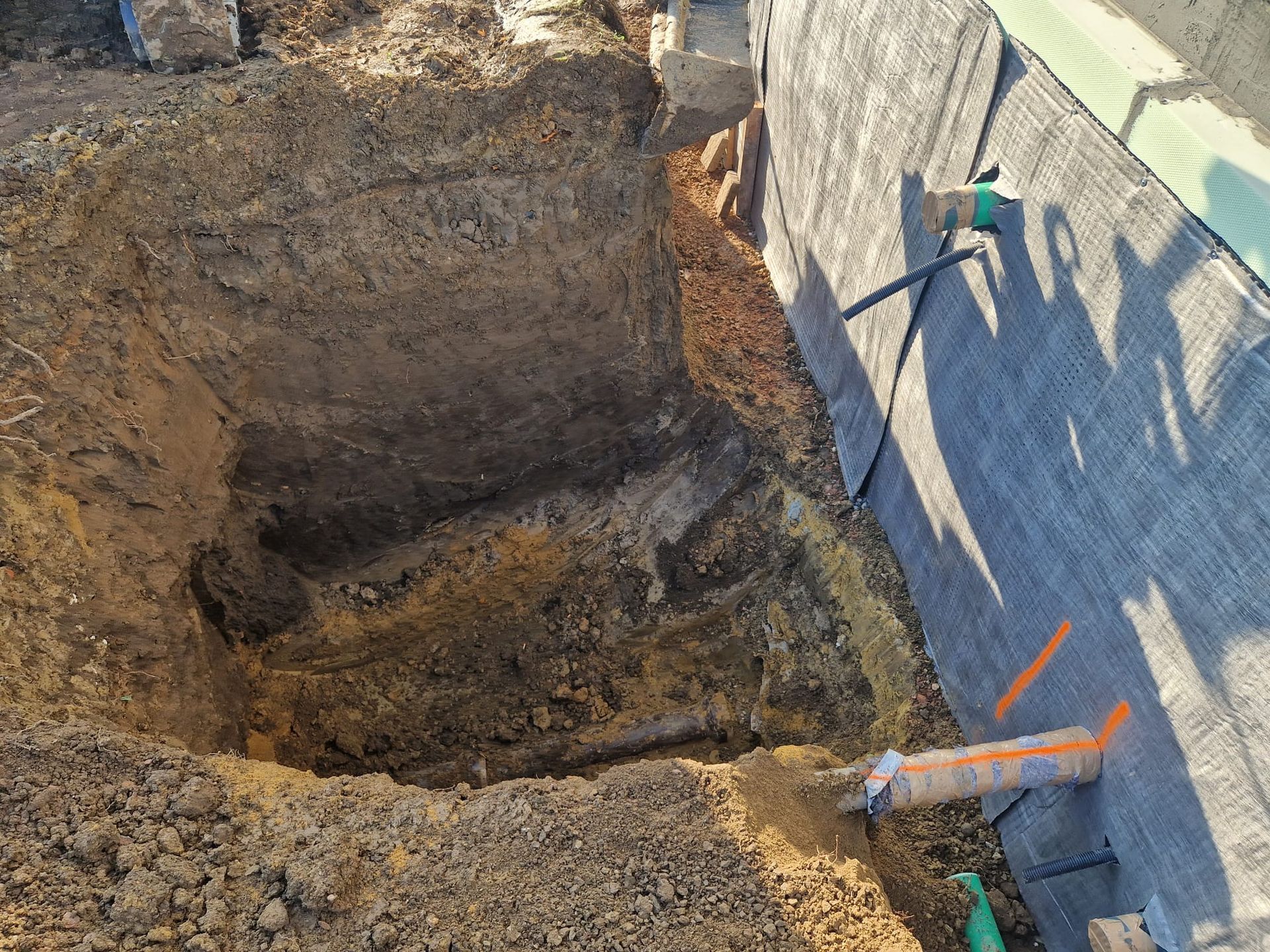 Ein großes Loch im Boden neben einer Mauer.