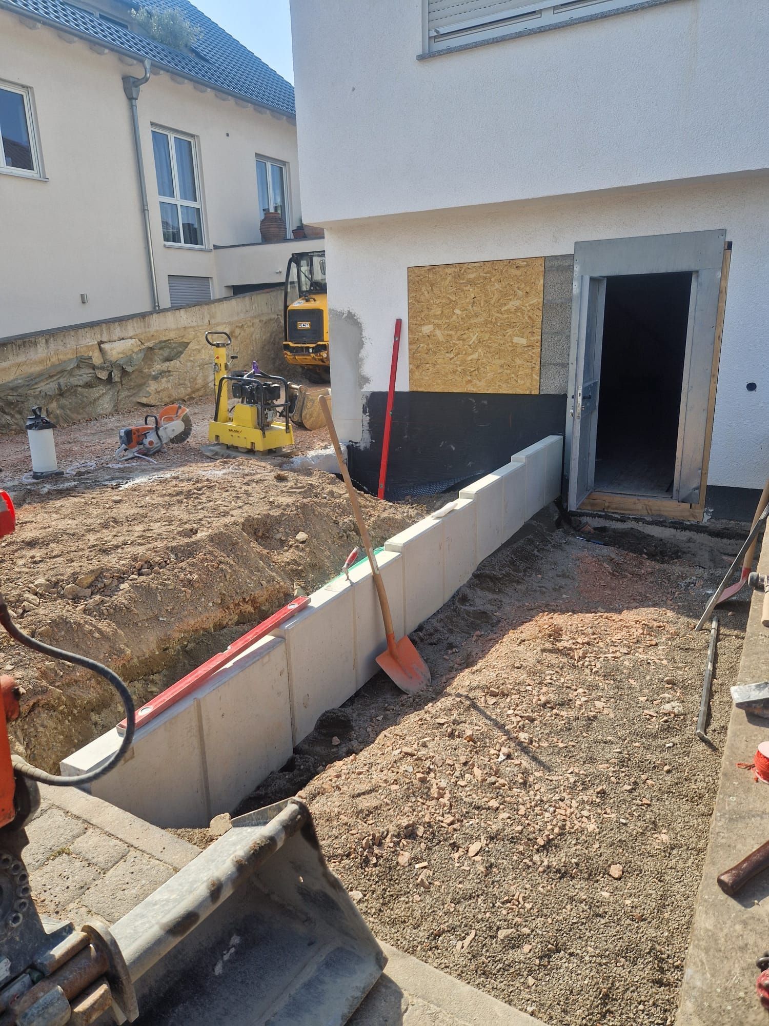 Eine Baustelle mit einem Gebäude im Hintergrund und einem Bulldozer im Vordergrund.