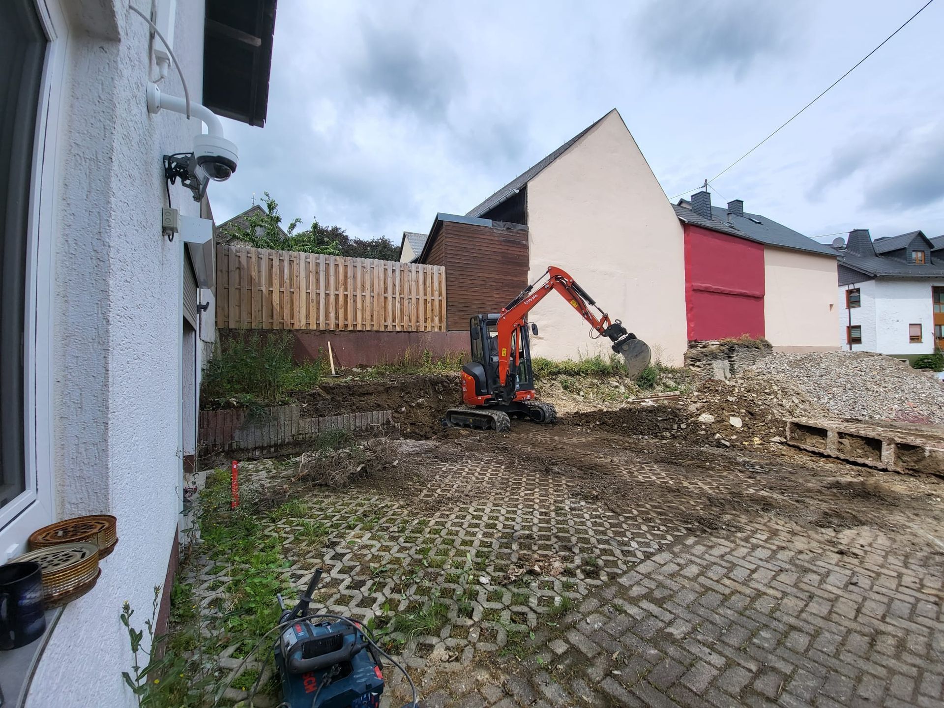 Ein Bagger gräbt ein Loch in die Erde vor einem Gebäude.