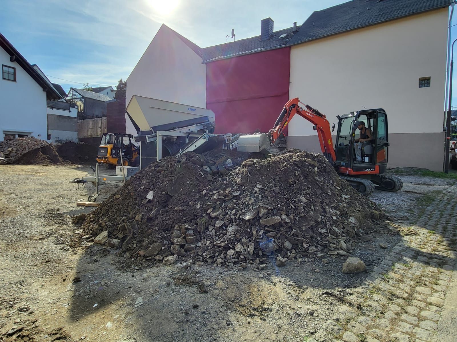 Vor einem Gebäude liegt ein Erdhaufen.