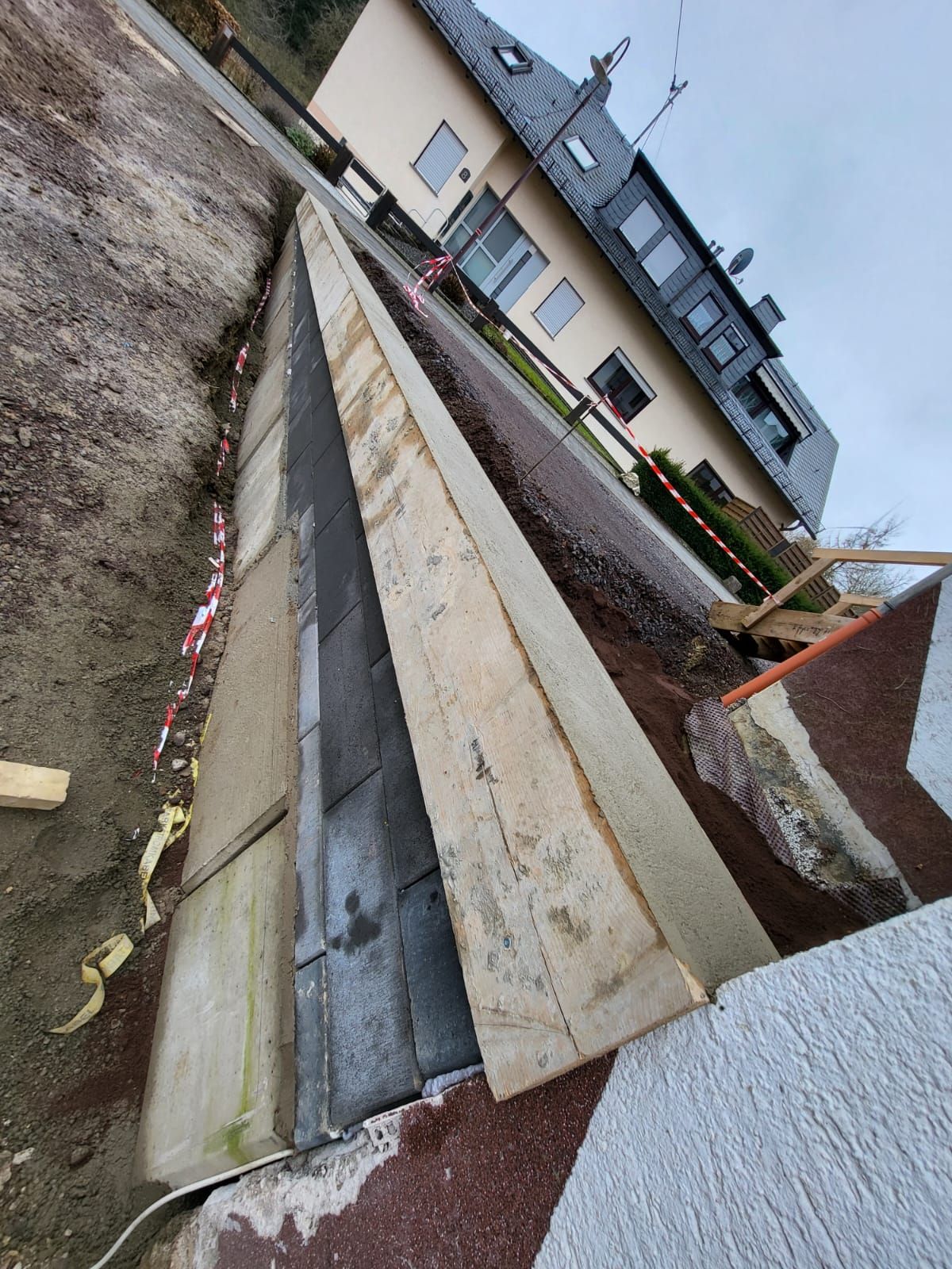 Im Hintergrund wird ein Haus gebaut und im Vordergrund wird eine Betonmauer errichtet.