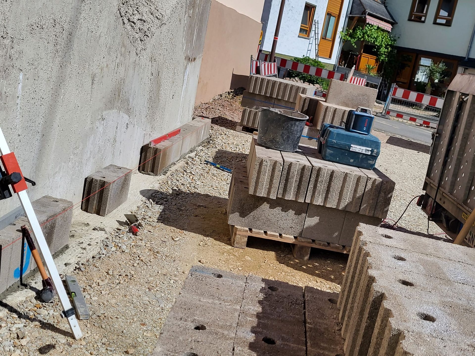 Auf einer Baustelle steht ein Stativ auf einem Stapel Ziegelsteine.