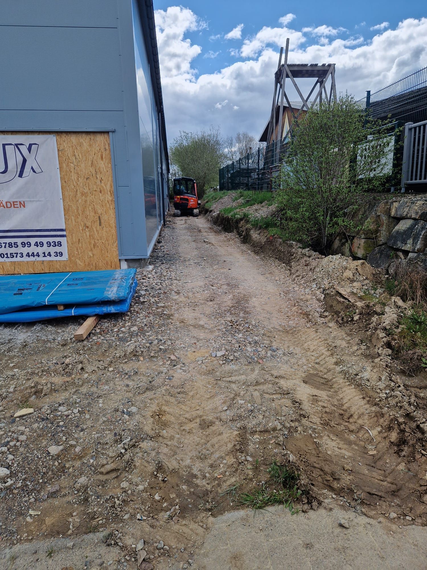 Ein Feldweg, der zu einem im Bau befindlichen Gebäude führt.