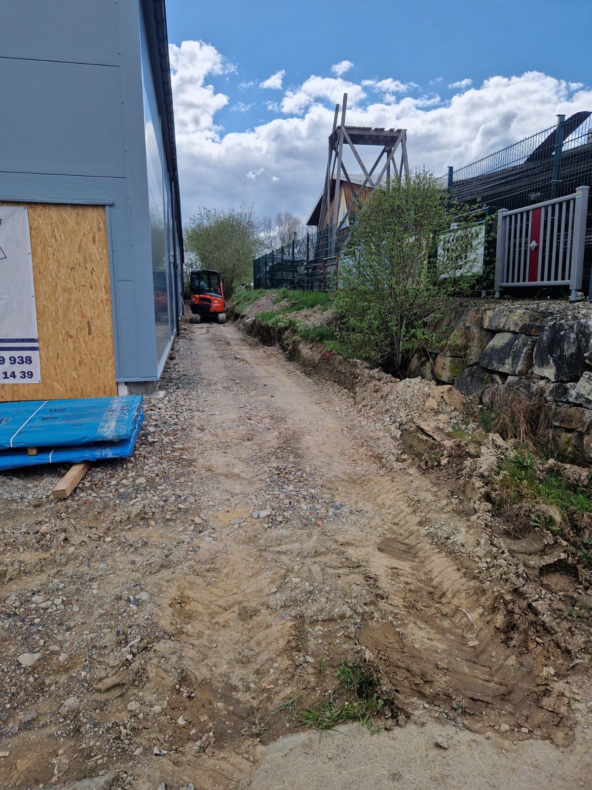 Ein Feldweg, der zu einem im Bau befindlichen Gebäude führt.