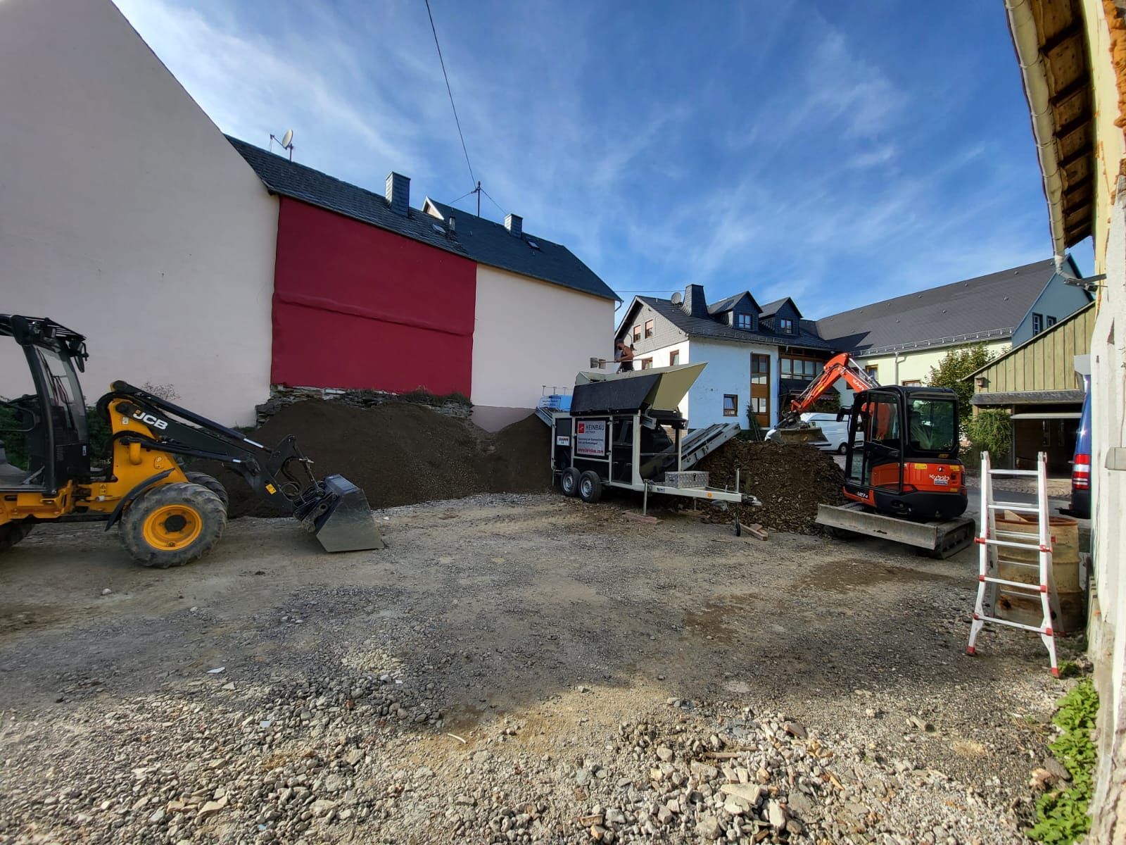Eine Baustelle mit einem Bulldozer und einer Leiter vor einem Gebäude.