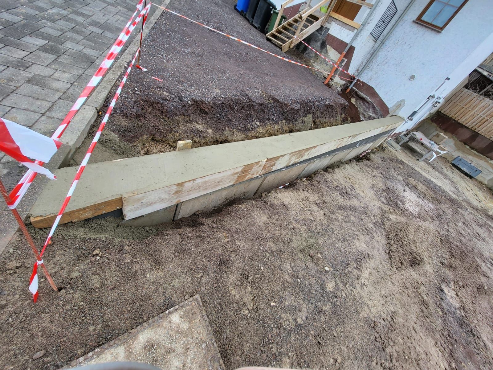 Vor einem Haus wird eine Betonmauer gebaut.