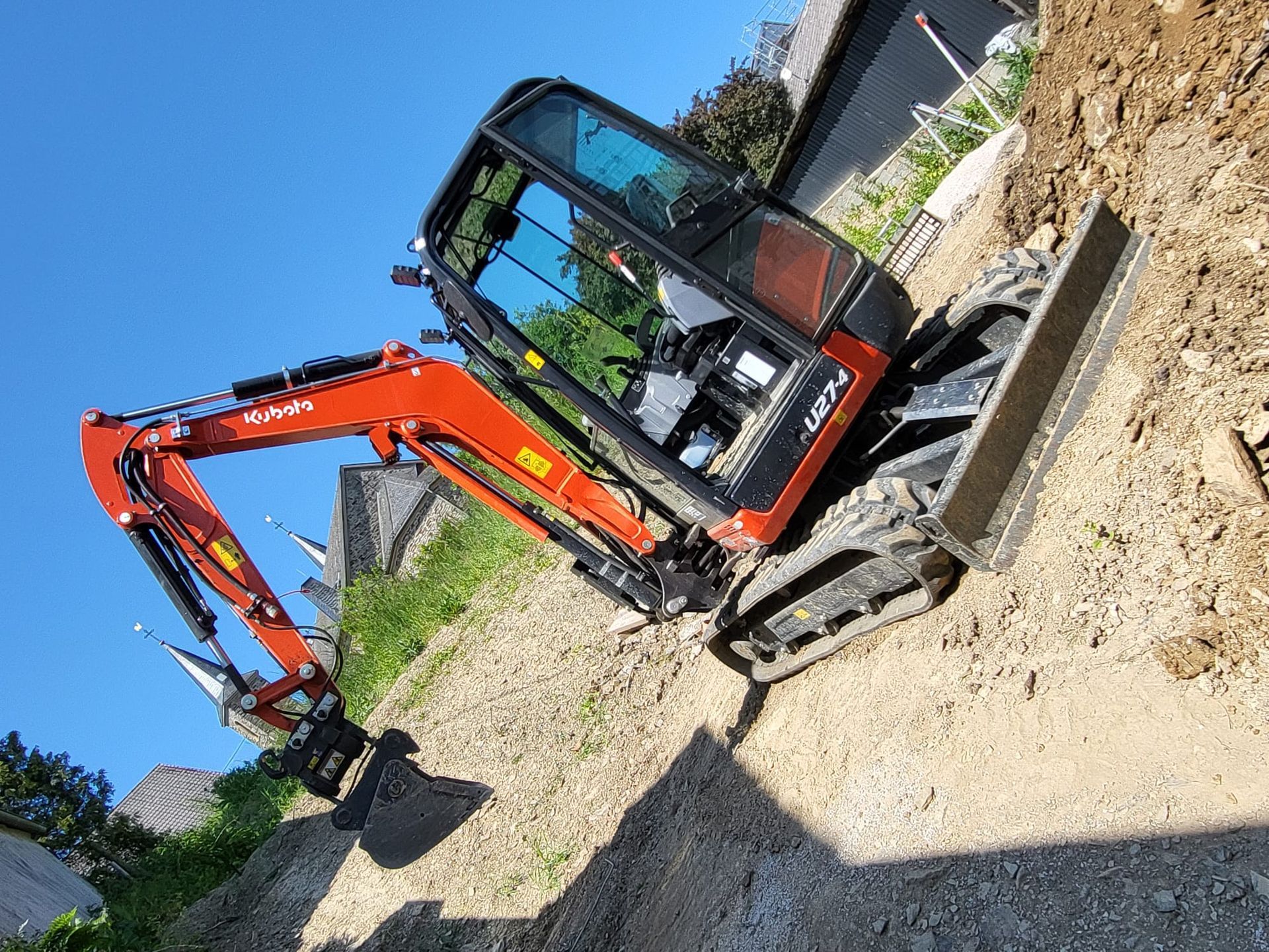 Ein kleiner roter Bagger steht auf einem Erdhaufen.
