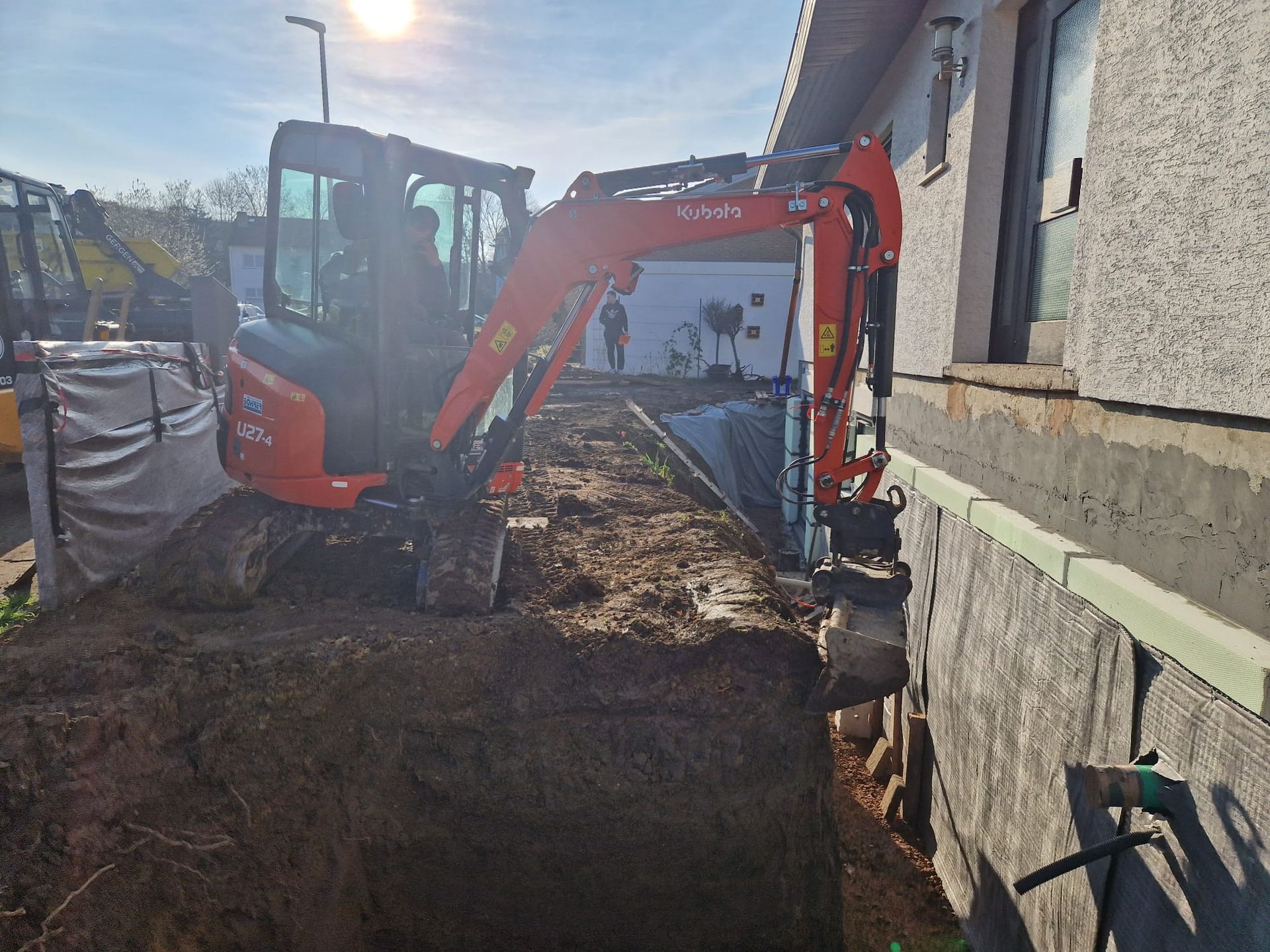 Ein Bagger gräbt vor einem Gebäude ein Loch.