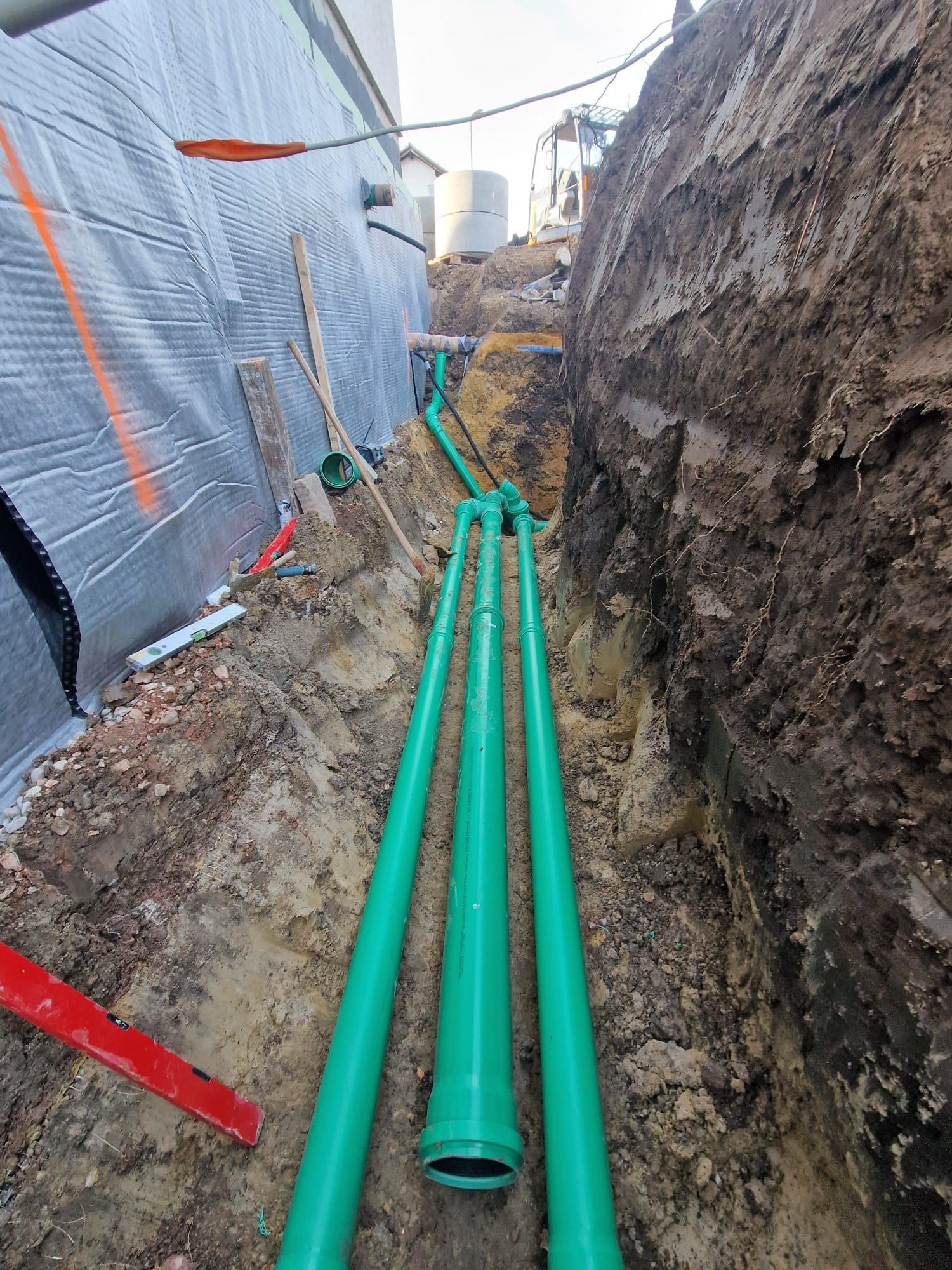 In einem Graben werden mehrere grüne Rohre verlegt.