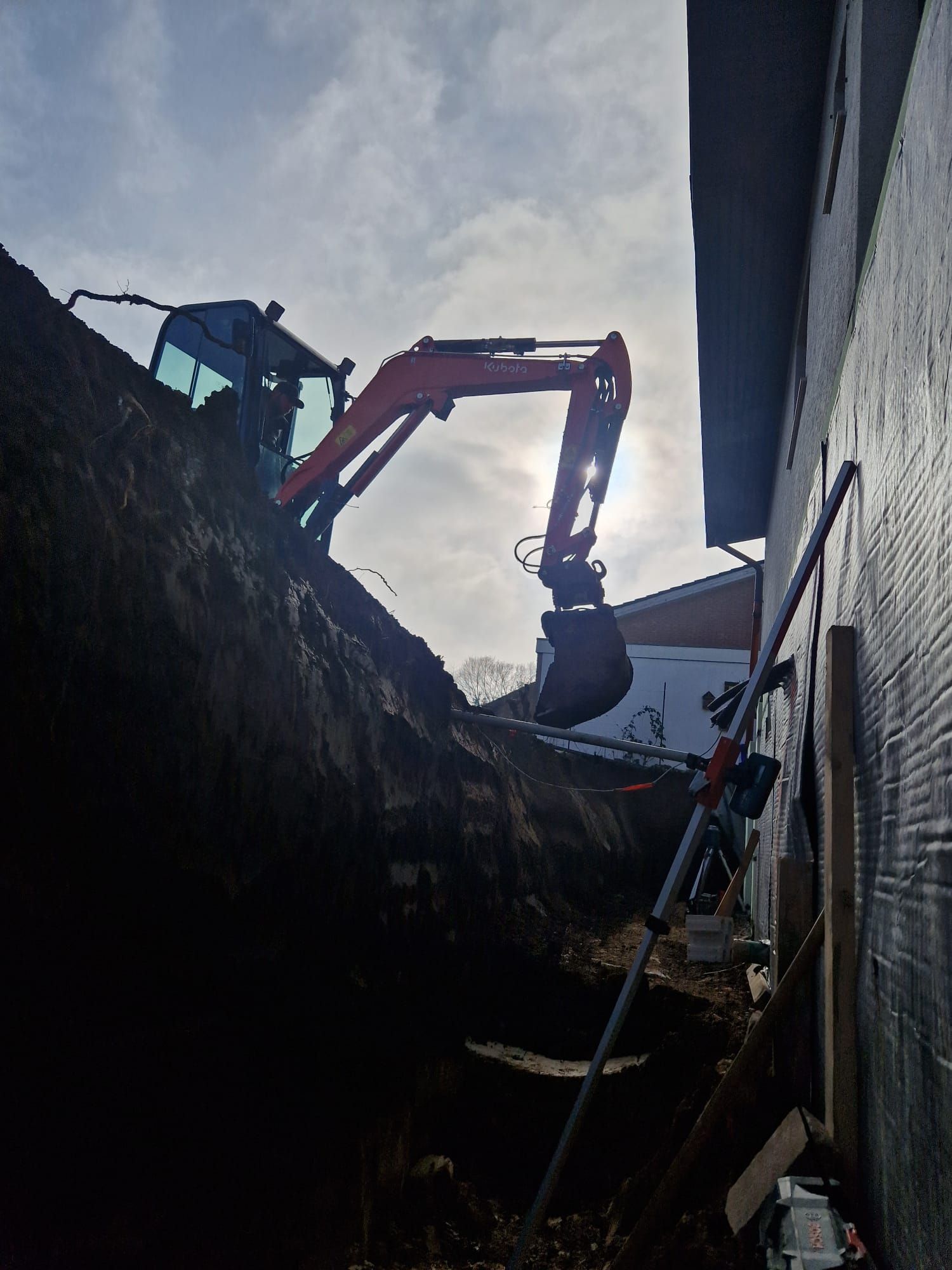 Ein Bagger gräbt ein Loch neben einem Gebäude