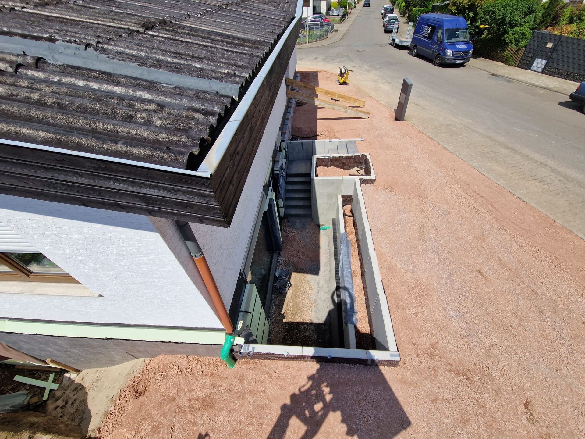 Eine Luftaufnahme eines Hauses mit einem am Straßenrand geparkten blauen Lieferwagen.