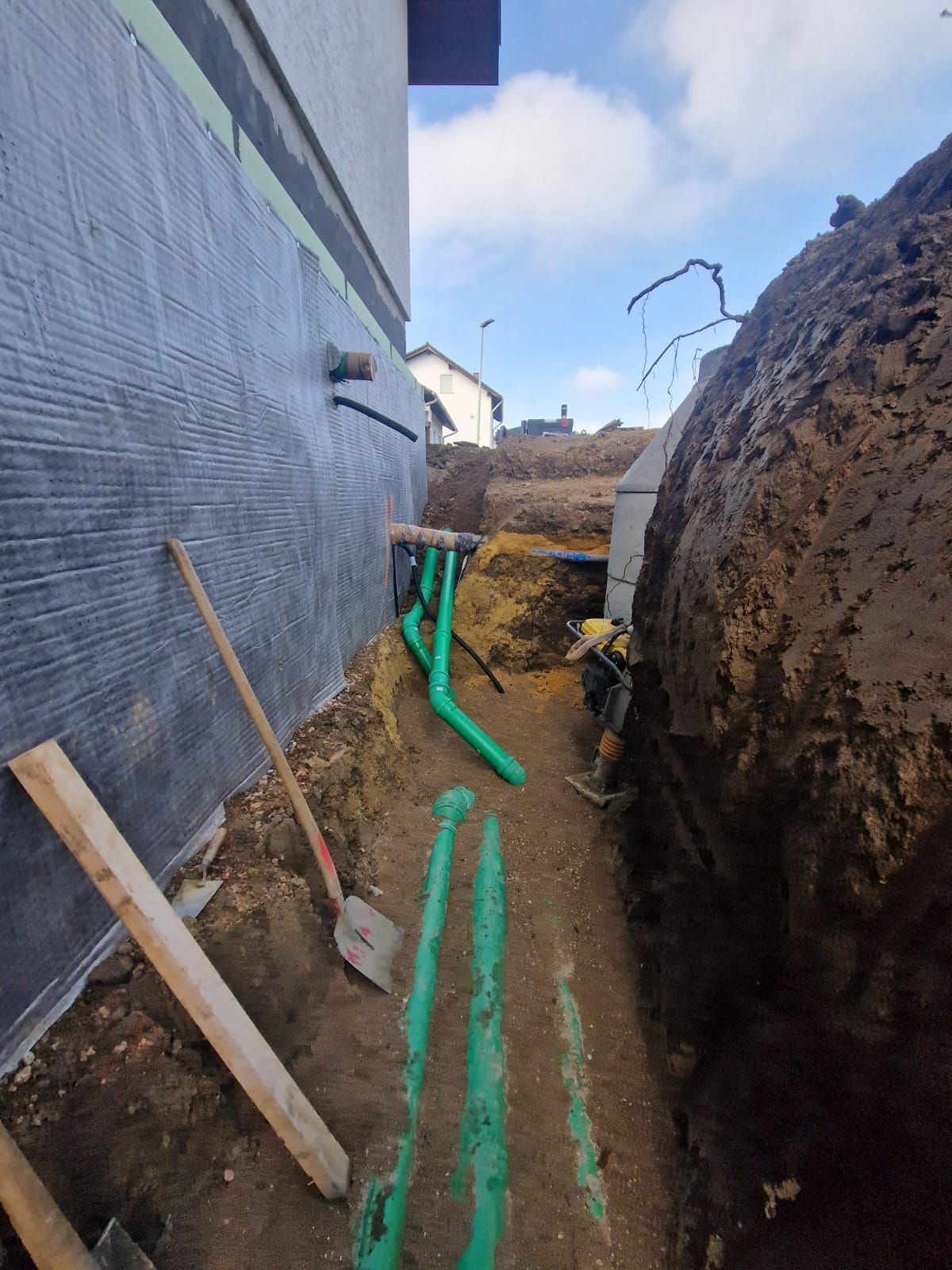Eine Baustelle mit grünen Rohren und Schaufeln im Dreck.