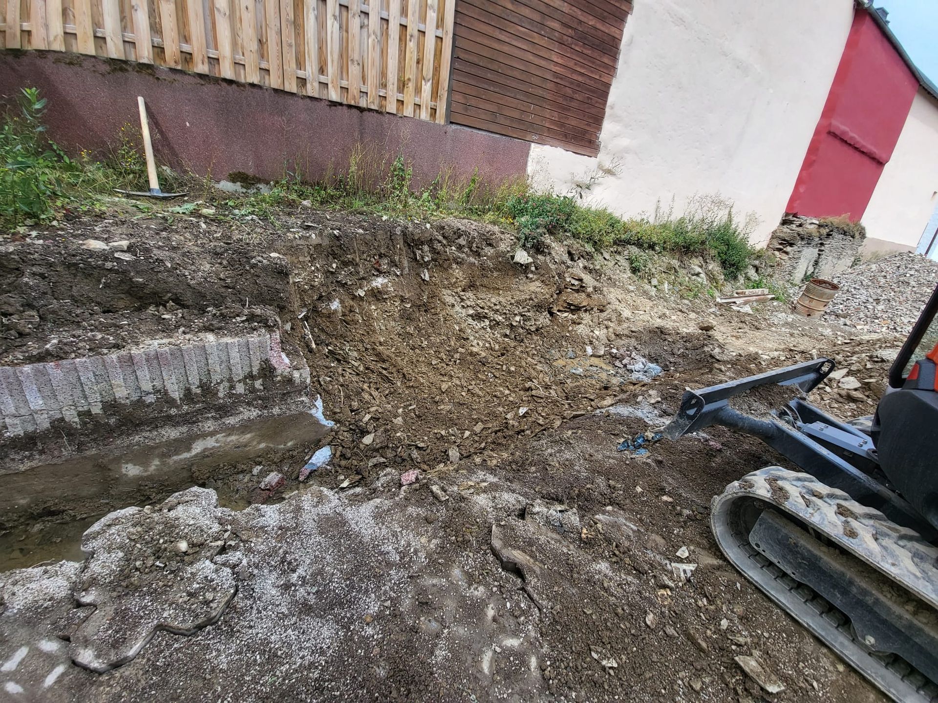 Ein Bulldozer gräbt ein Loch in die Erde vor einem Gebäude.