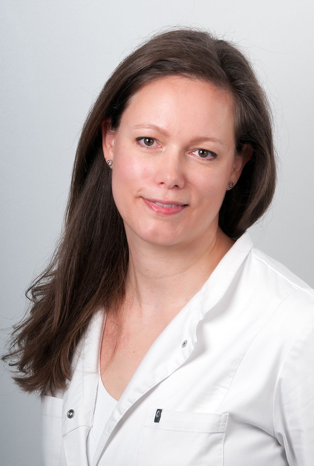 Eine Frau im weißen Laborkittel lächelt in die Kamera.