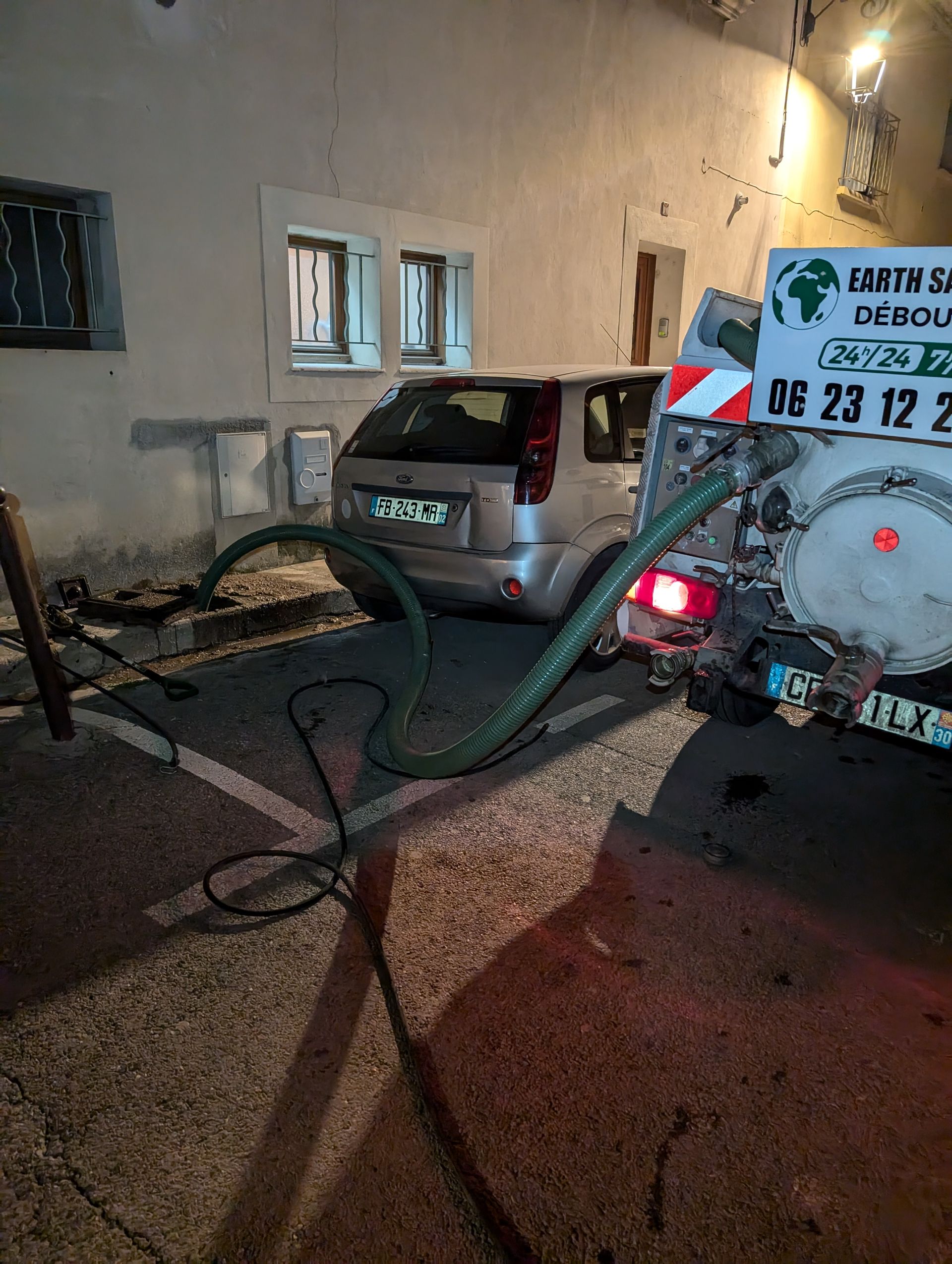 Camion de débouchage avec un tuyau passé dans une canalisation d'une maison particulière.