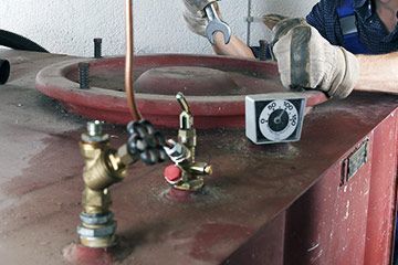 Ein Mann arbeitet mit einem Schraubenschlüssel an einem Tank.