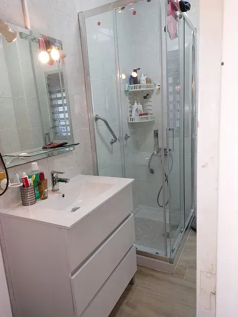 Un baño con lavabo, espejo y cabina de ducha.