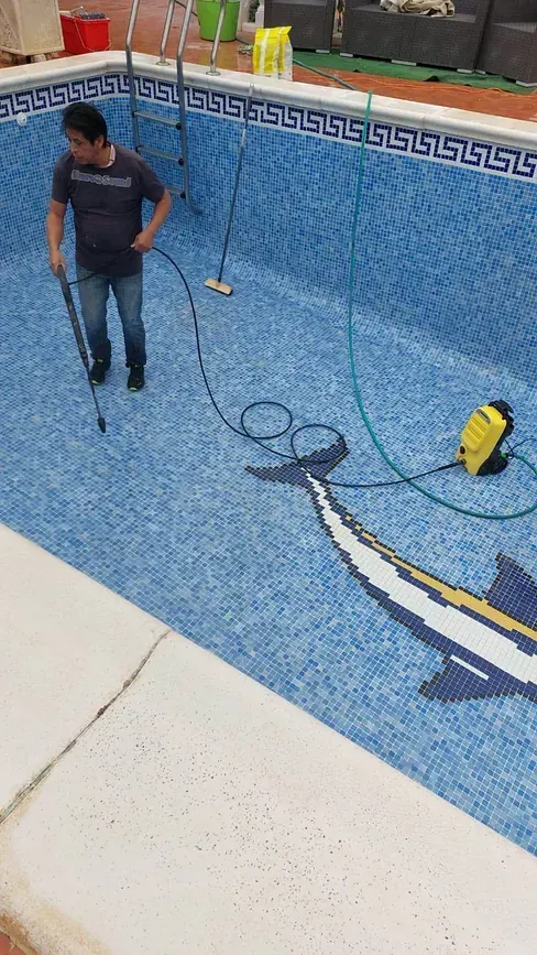 Un hombre está limpiando una piscina con una aspiradora.