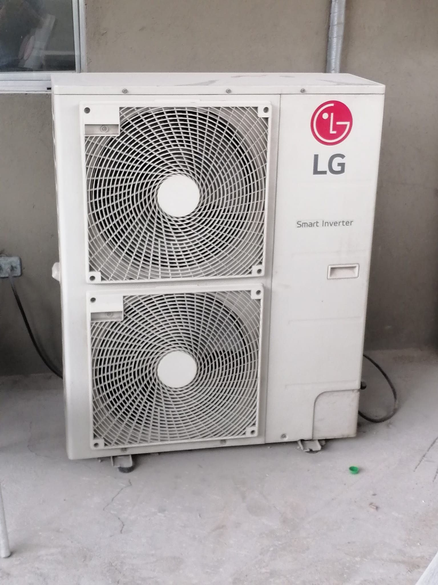 Dos unidades exteriores de aire acondicionado LG blancas montadas verticalmente en la pared de un edificio.