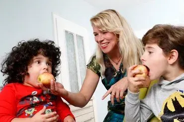 Eine Frau und zwei Kinder essen zusammen Äpfel.