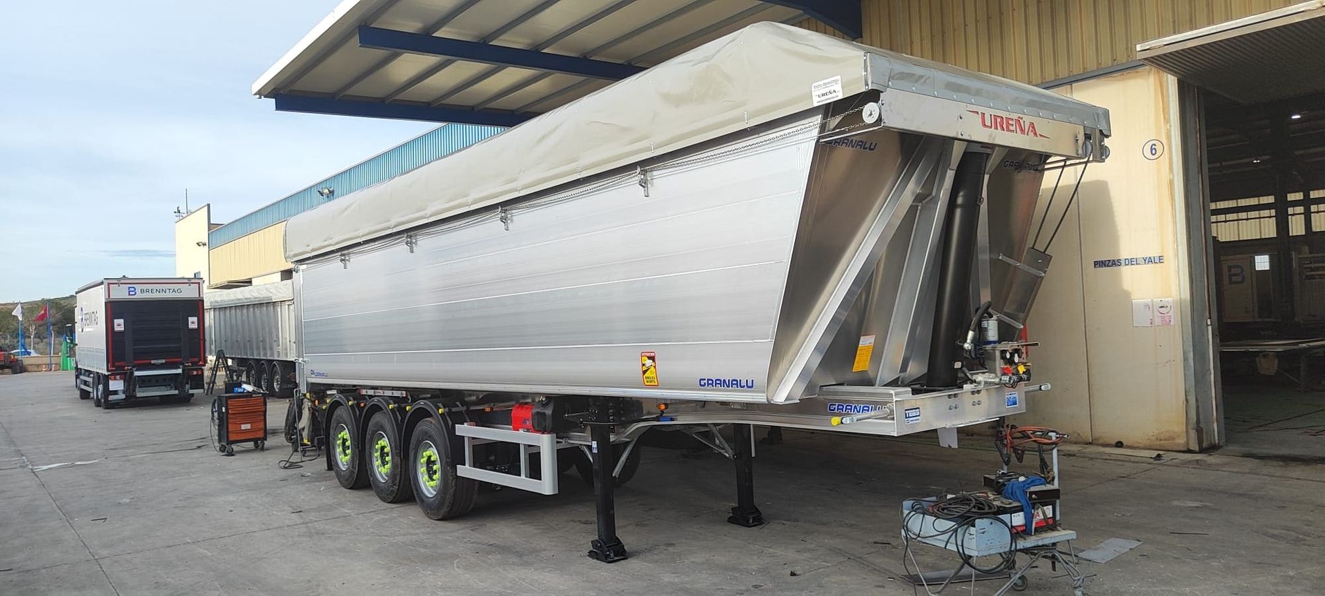 Un escritorio con una computadora portátil, lápices, una tableta y una pequeña casa encima.