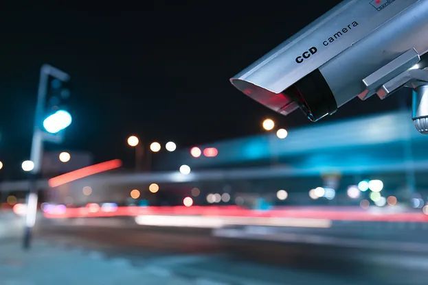 Una cámara de seguridad está situada en lo alto de una calle por la noche.