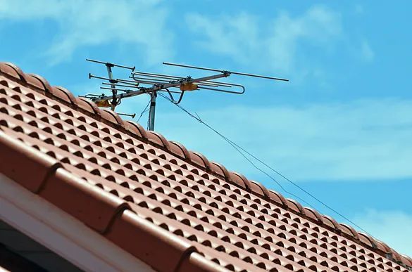 Una antena está colocada encima de un tejado de tejas.