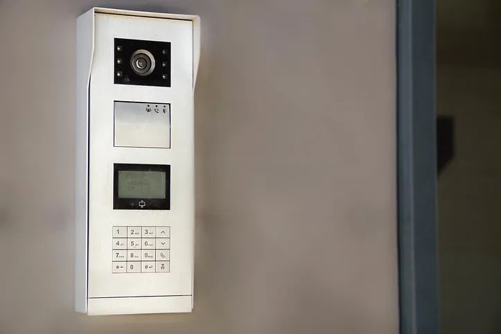 Un timbre blanco está colgado en una pared al lado de una puerta.