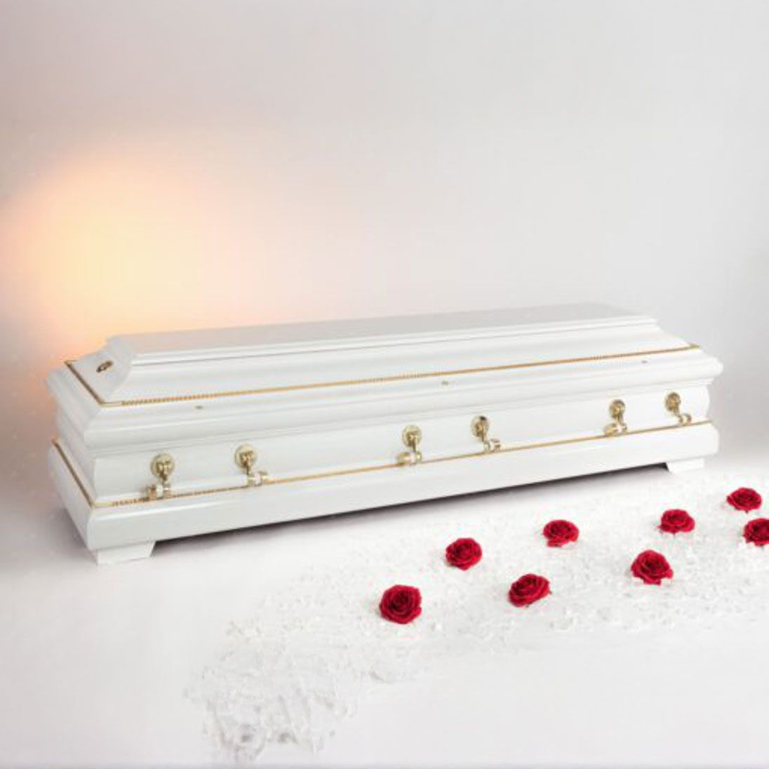 Weißer Sarg mit goldenen Verzierungen, elegant präsentiert.