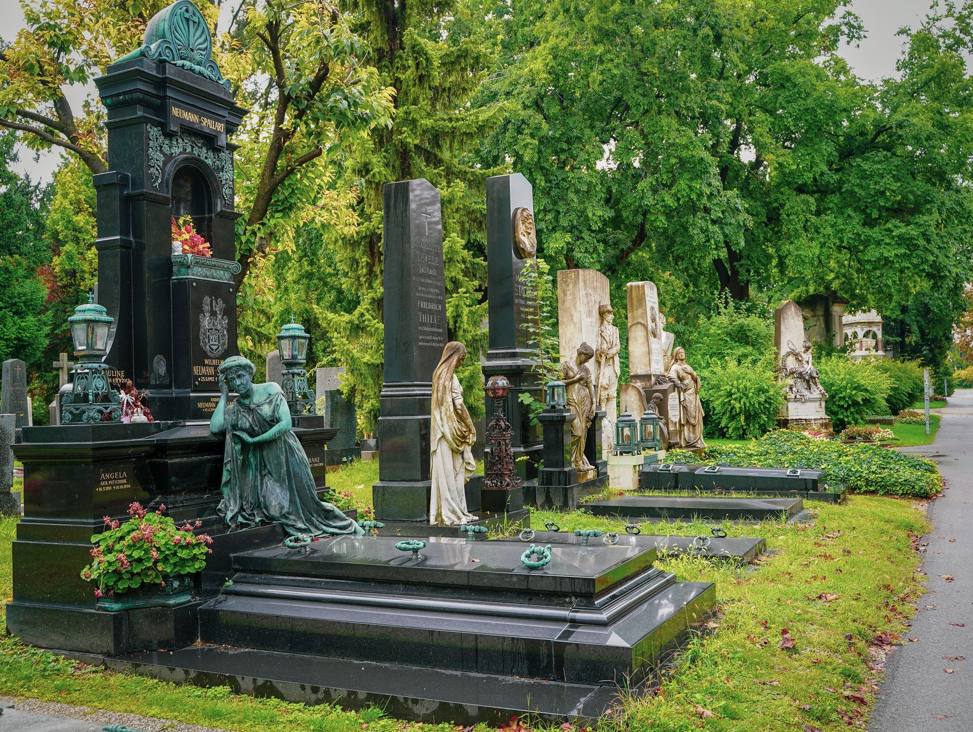 Grab mit Holzkreuz und buntem Blumenschmuck auf einer Wiese, liebevoll gestaltet zur Erinnerung an Verstorbene.