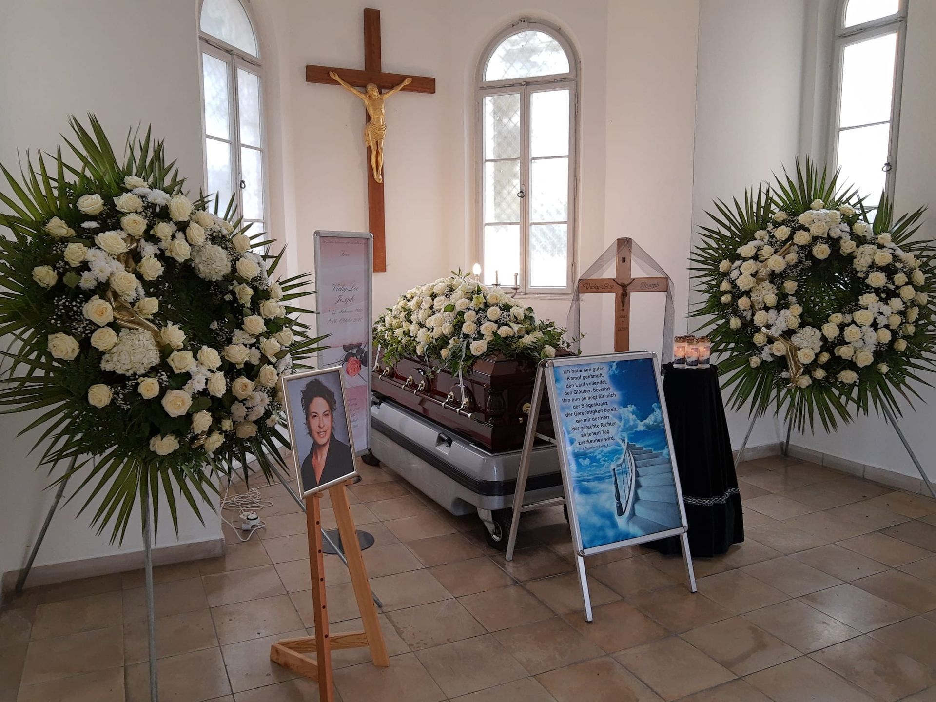 Trauerfeier innen: Sarg mit Blumen, Kerzen und Gedenkportrait.