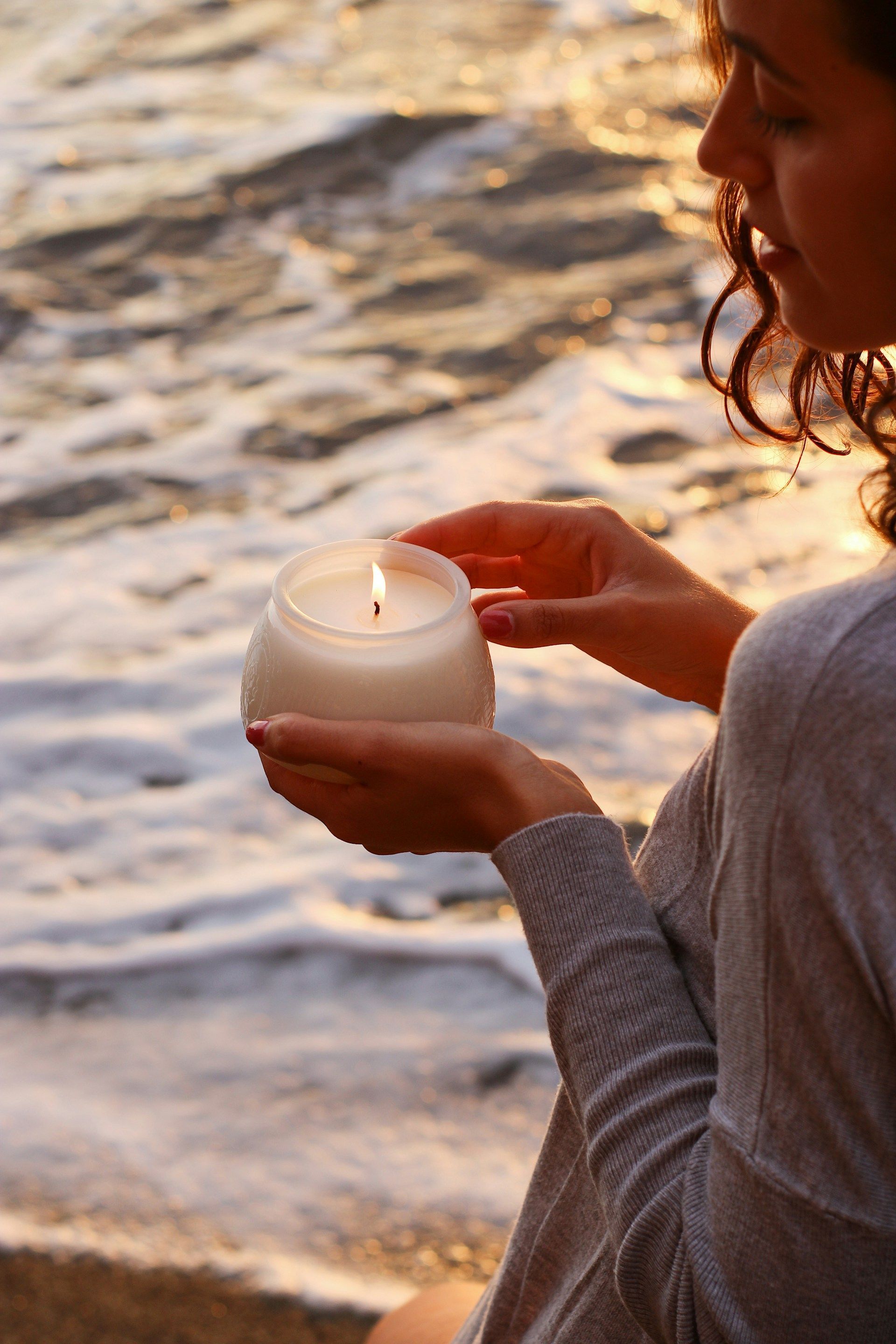 Hände streuen bunte Blüten ins Wasser als symbolischer Abschied oder Gedenkritual.