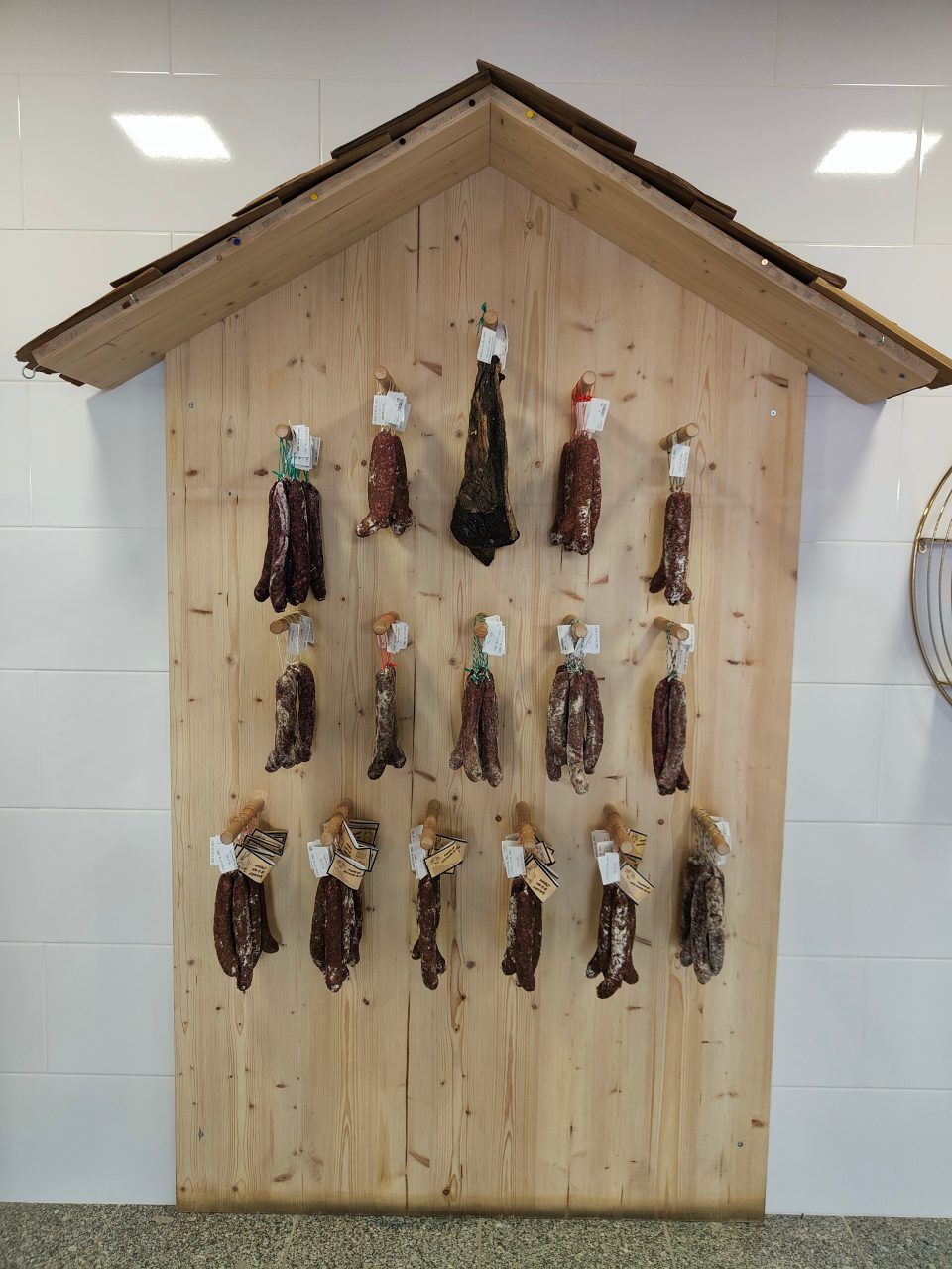 Un mur en bois sur lequel est accrochée de la viande en forme de maison.