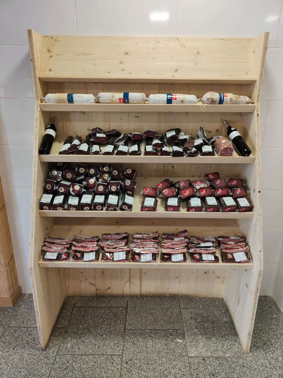 Une étagère en bois remplie de produits carnés dans un magasin.