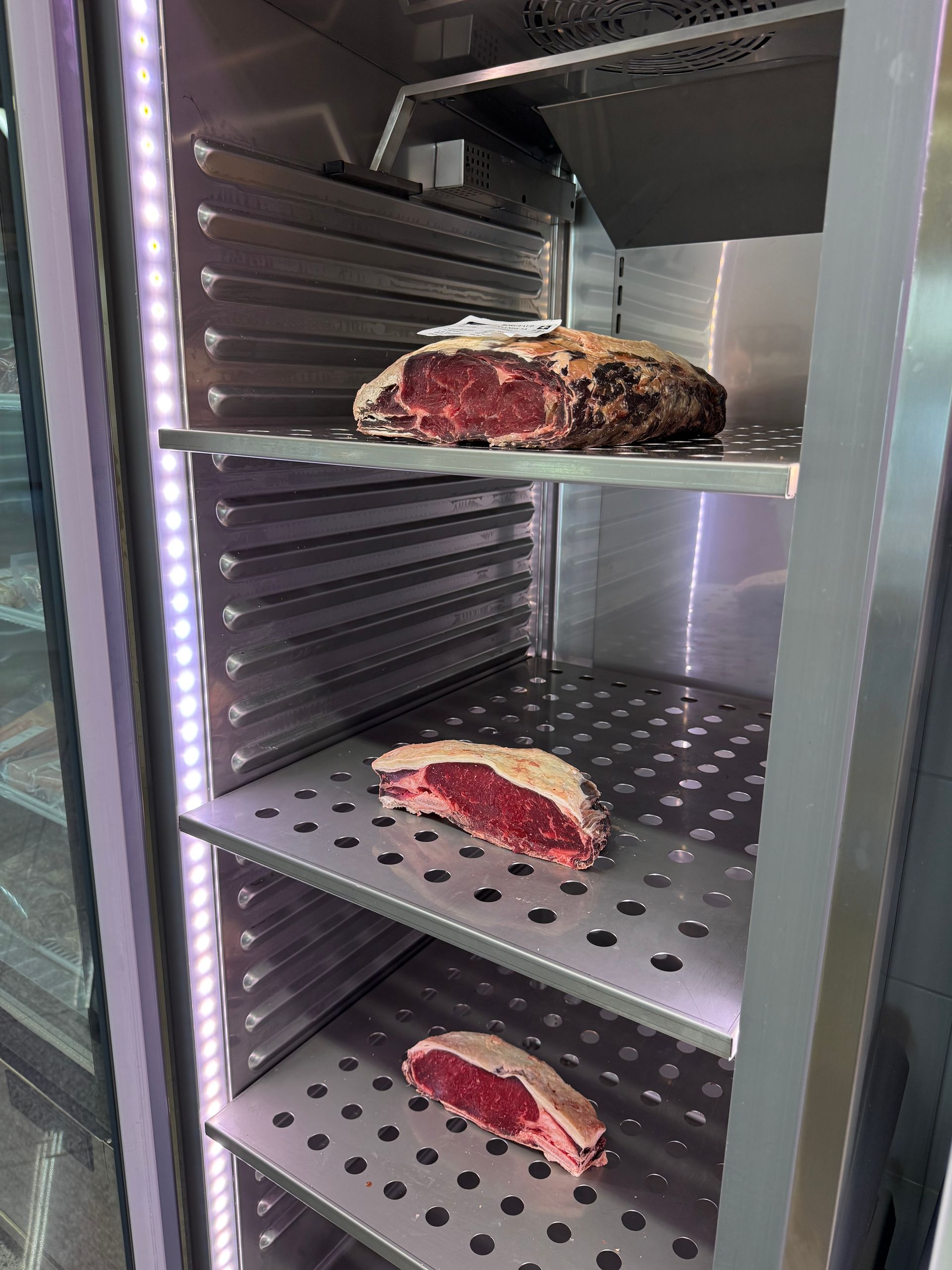 Une personne tient un steak cru sur une planche à découper.