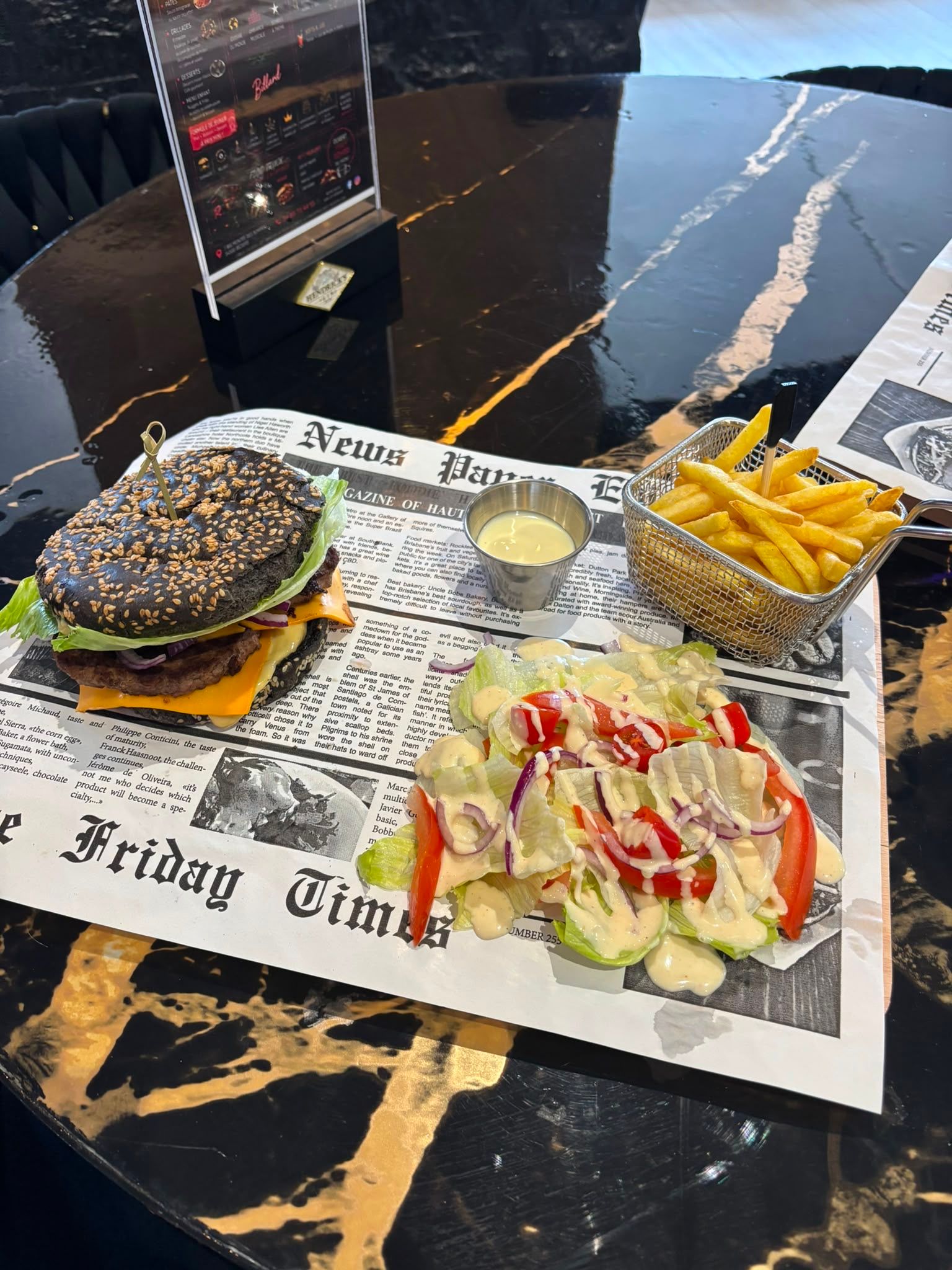 Des hamburgers et de la bière sur une table en bois dans un pub chaleureux, avec des personnes floues en arrière-plan.