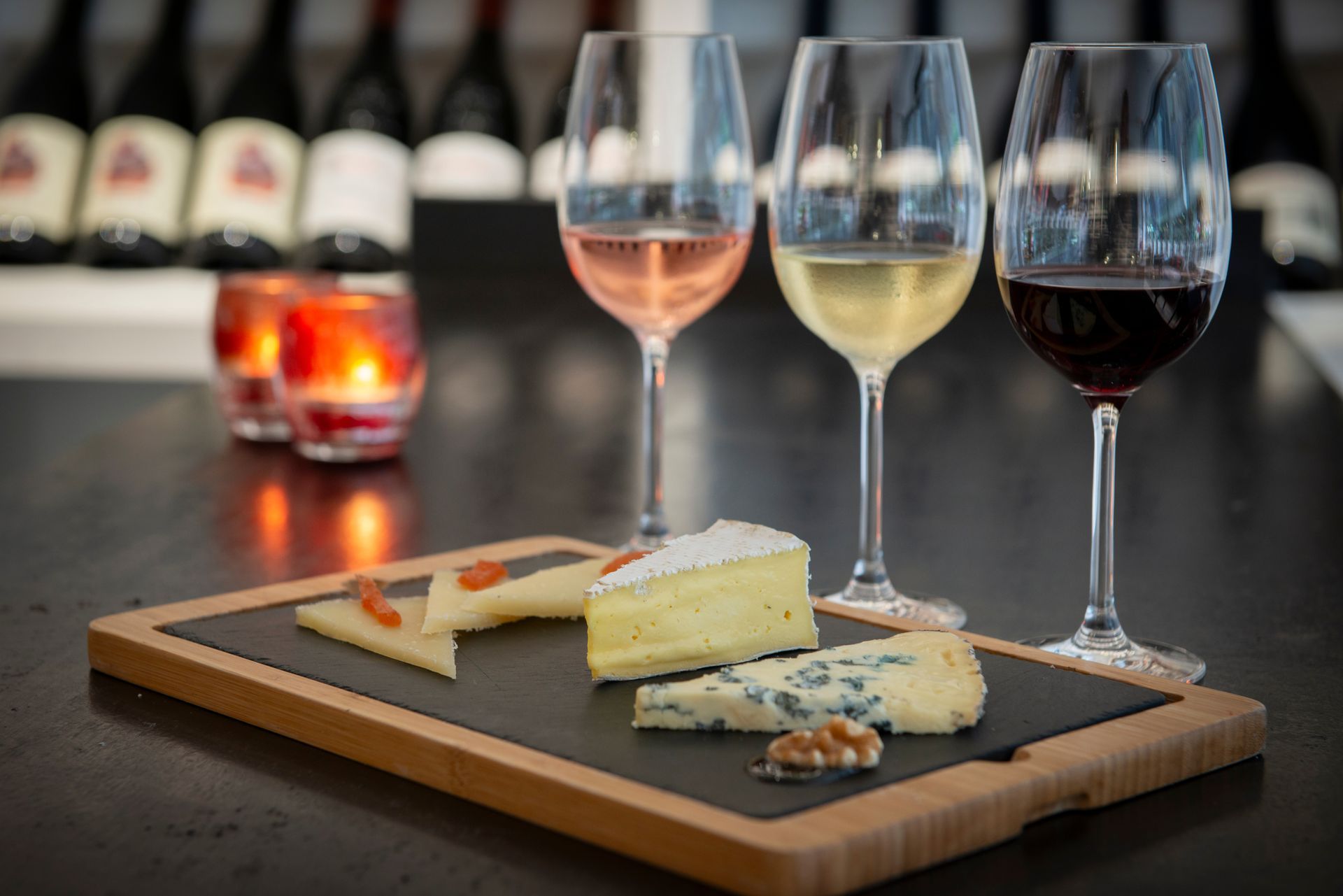 Des verres à vin blanc et rouge à côté d'un plateau de fromages sur une table