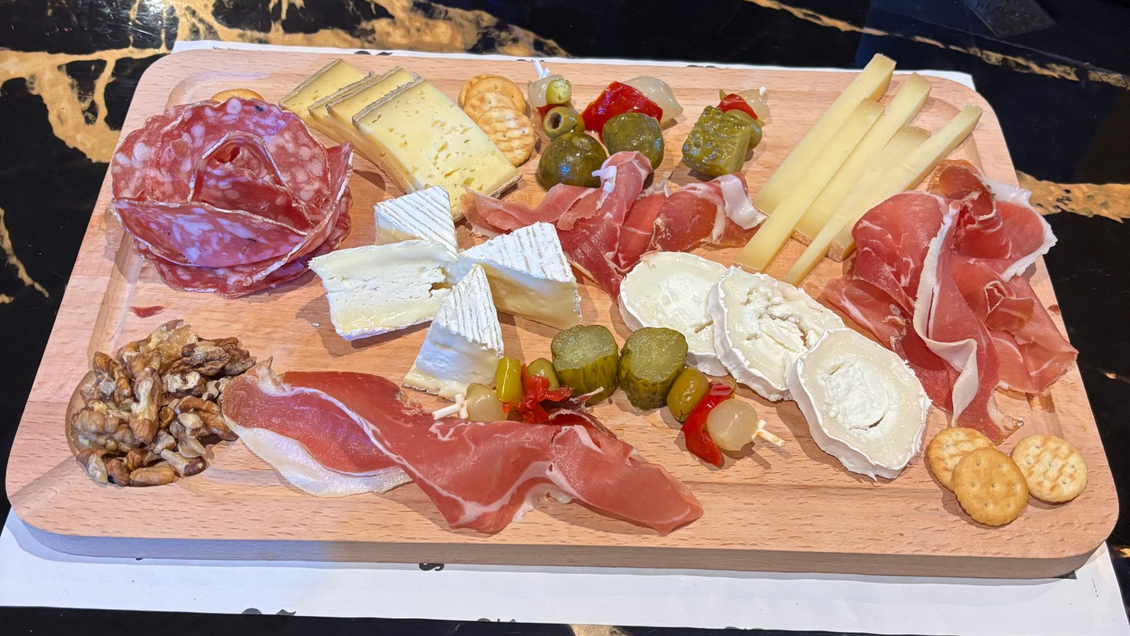 Dégustation de vins et de fromages présentés sur une planche en bois avec trois verres et un assortiment de fromages.