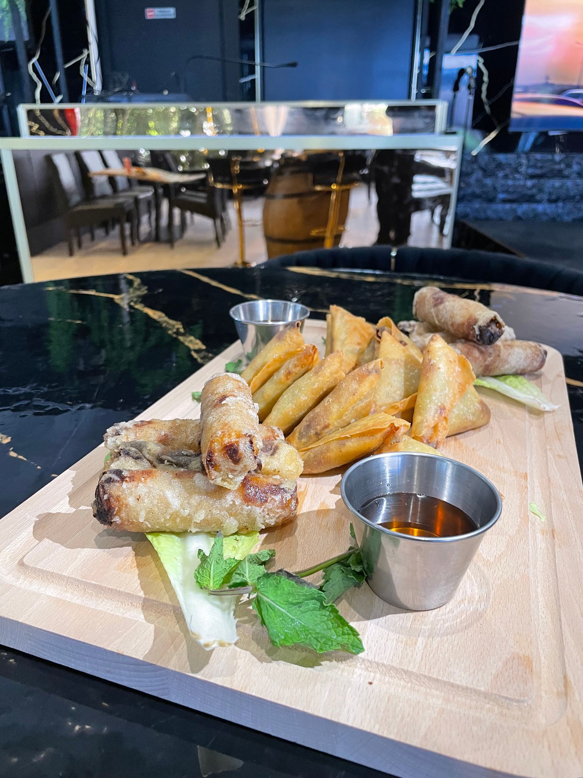 Un cocktail à côté d'un plateau de fruits de mer frits et de sa sauce, sur une table de restaurant.