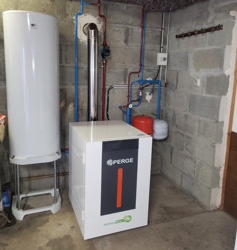 Poêle à granulés et chauffe-eau dans un sous-sol aux murs de briques et aux tuyaux apparents.