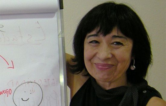 Una mujer está parada frente a una pizarra con una cara sonriente dibujada en ella.
